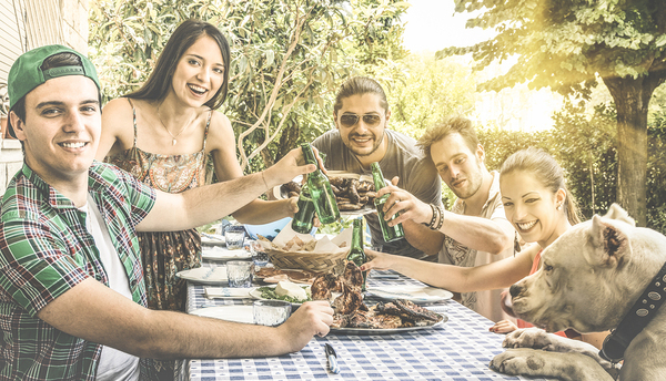 Group of young men and woman at an outside table eating and drinking