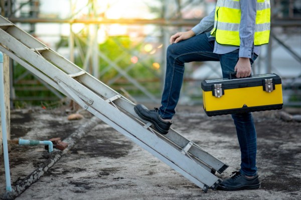 man about to climb a ladder with his toolbox