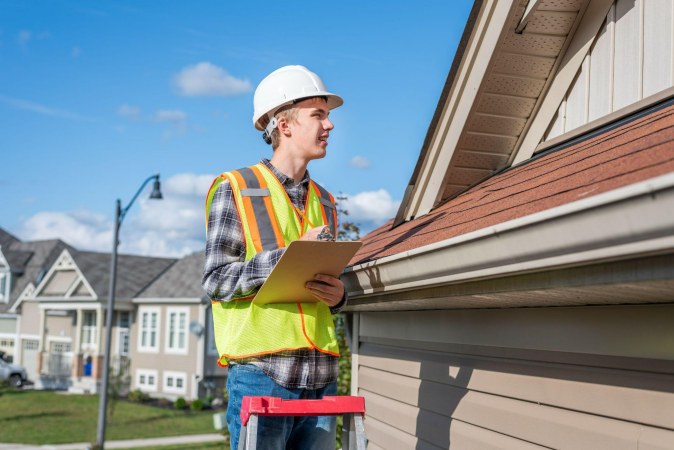 young man evaluating a house roof